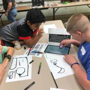 Three children playing with an Ozobot 