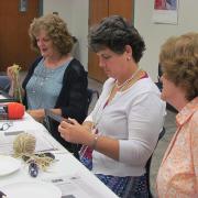 Craft program attendees begin adding yarn to their frames.
