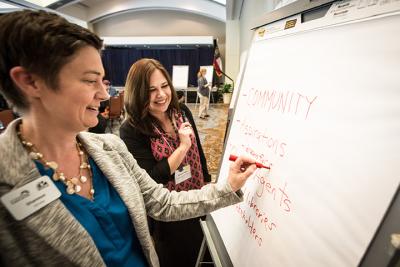 Two women writing on a write board at a Public Innovators Lab