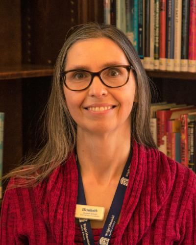 Photograph of Elizabeth Schmidt in front of bookshelf.