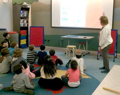 Students sitting on the floor and looking at a slide during the Adventure Club program