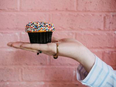 Hand holding out a cupcake