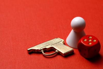 Red background with a white board game piece, a piece shaped like a gun and a red and white dice.