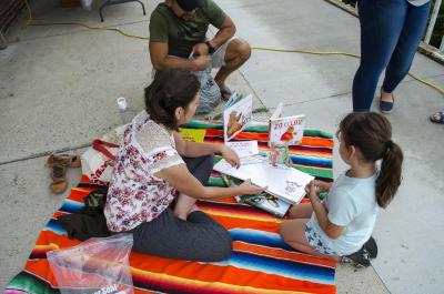 Woman and child sit on blanket and look at books.