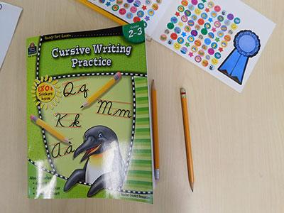 A cursive writing practice workbook and some stickers
