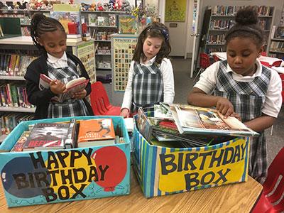 Girls looking through a box of books in a library