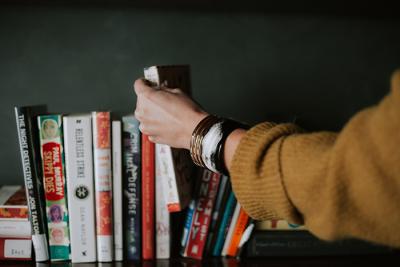 Hand reaching out and selecting a book from several on a shelf