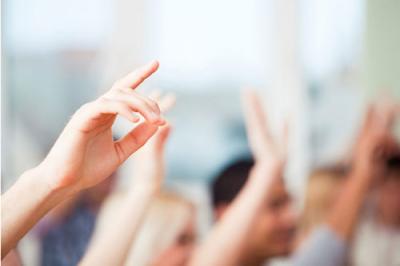 Hands raised in the air, as in a classroom