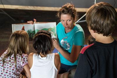 Woman reading a story aloud to a group of children