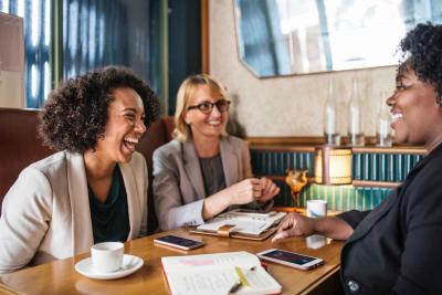 Three women sitting around a table, laughing