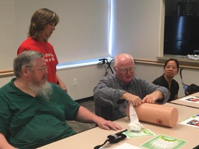 Group of people watching a man learning first aid