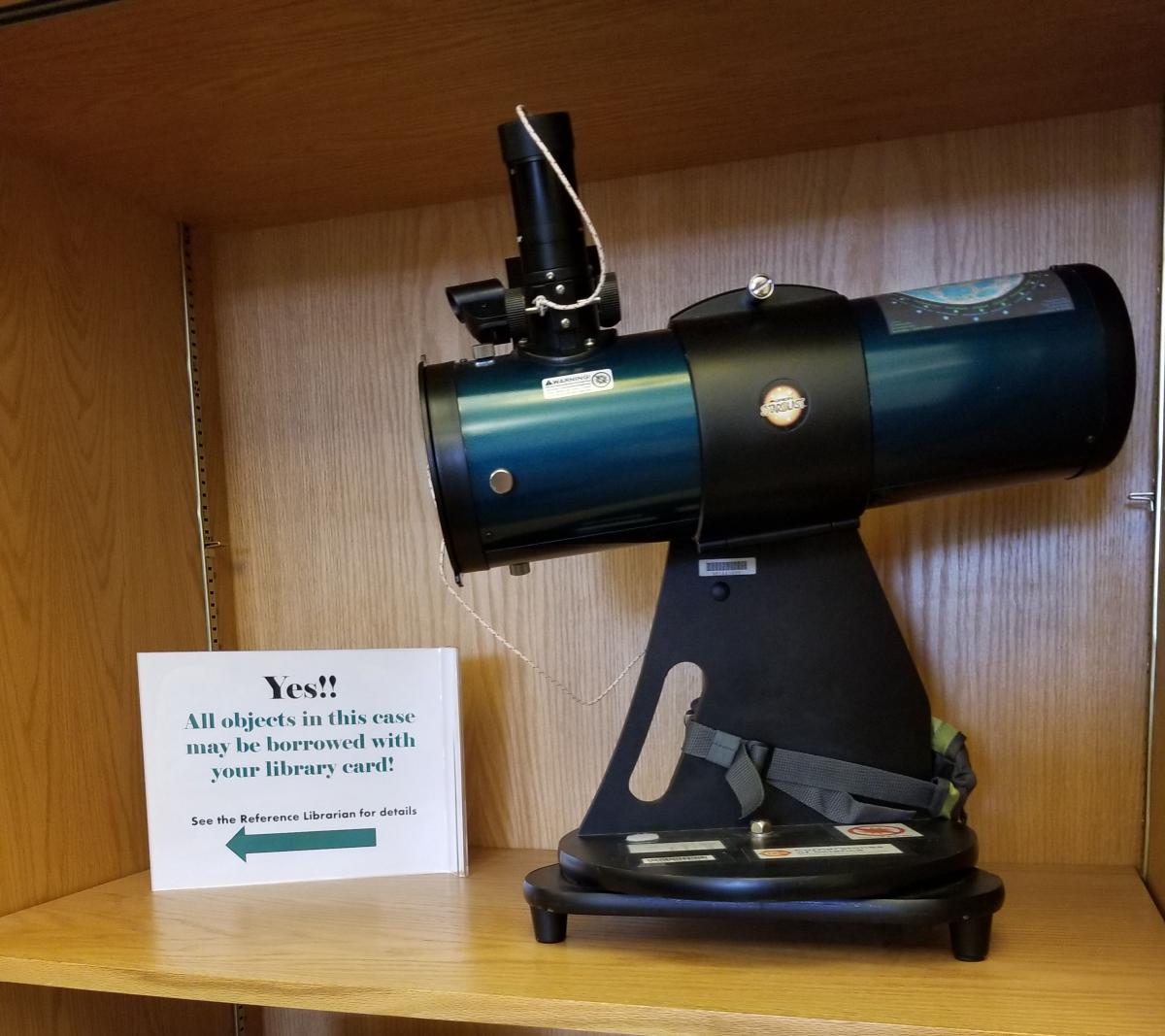 Microscope sits on brown bookshelf.