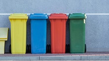 four trash bins on sidewalk