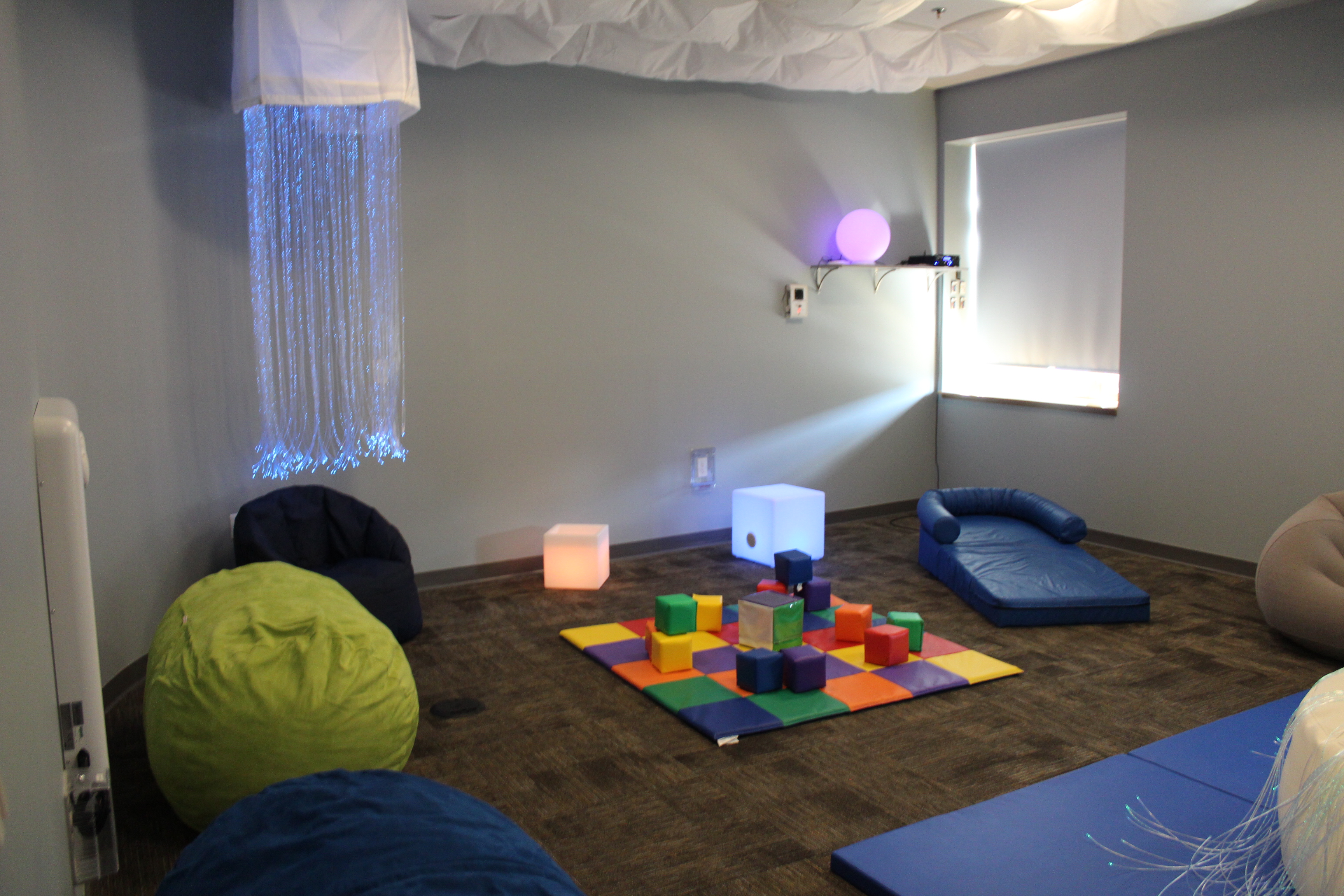 Photograph of Ocean County Library's Sensory Space. The photograph shows the room with a the hanging LED lights, bean bags, tactile tiles, LED boxes and plush floor.