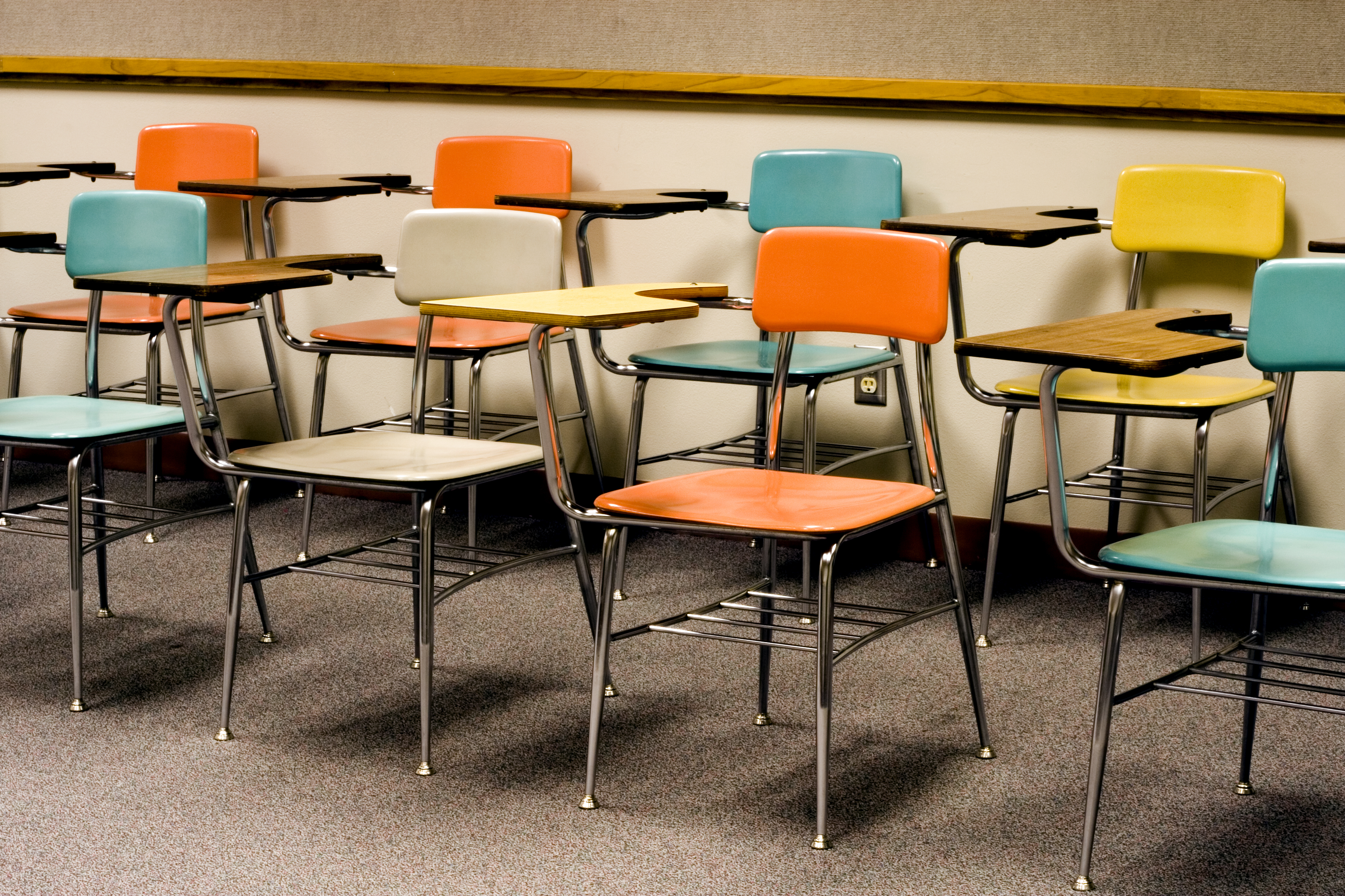 Photograph of two rows of empty desks inside a classroom.